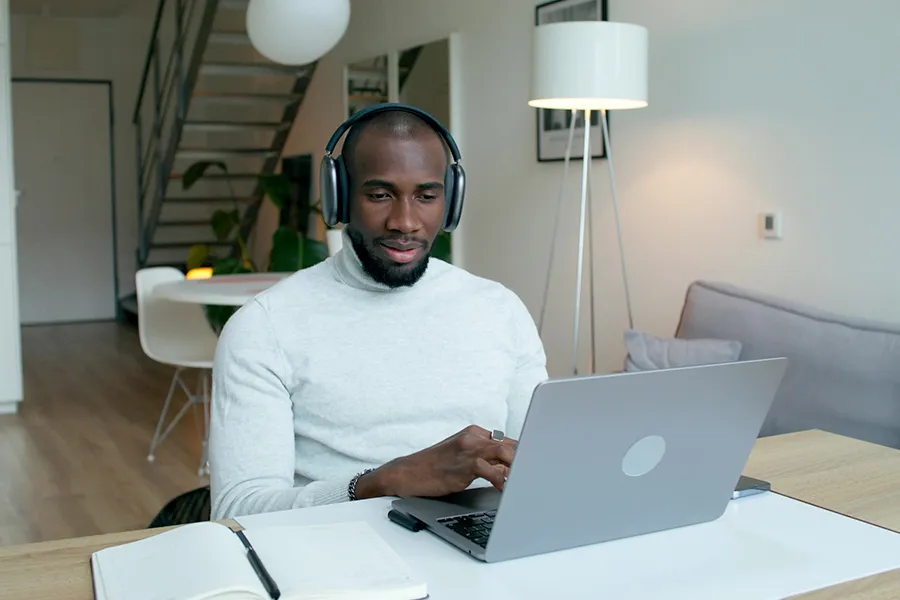Un homme portant un casque audio, travaillant devant son ordinateur chez lui